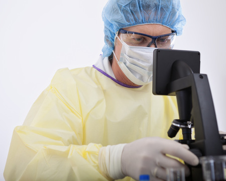 portrait of scientist or doctor in protective gear working with microscope and blood, in lab or hospitalの写真素材