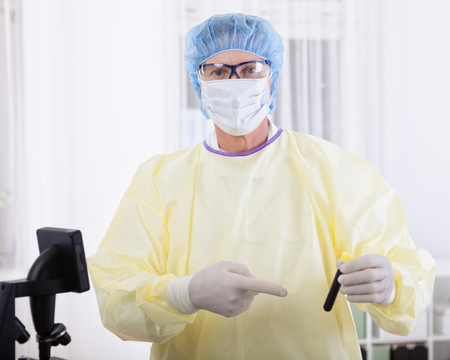 portrait of scientist or doctor in protective gear working with microscope and blood, in lab or hospitalの写真素材