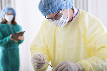 two scientist or doctors in protective gear working with microscope and blood, in lab or hospitalの写真素材