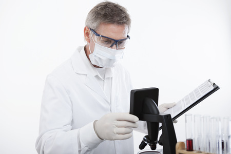 scientist or doctor working with clipboard, microscope and blood, in lab or hospitalの写真素材