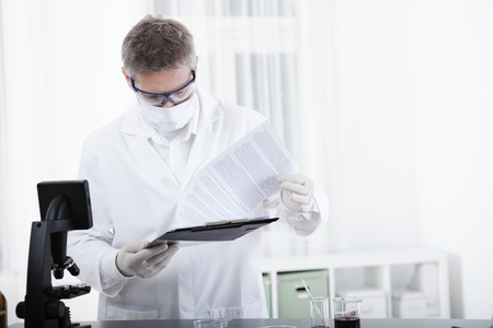 scientist or doctor working with clipboard, microscope and blood, in lab or hospitalの写真素材