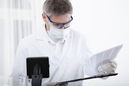 scientist or doctor working with clipboard, microscope and blood, in lab or hospitalの写真素材