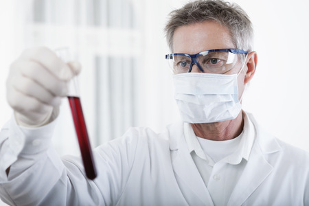 scientist or doctor looking on blood test tube, in lab or hospitalの写真素材