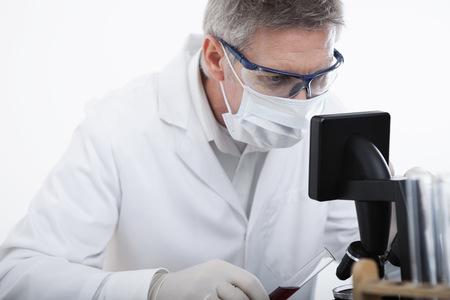 scientist or doctor looking on microscope and analyse blood test tube, in lab or hospitalの写真素材