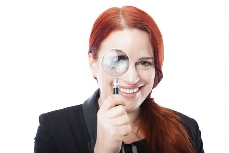 Pretty Young Businesswoman Spying Through Magnifying Glass Over the Eye with Open Mouth and Winking Eye. Isolated on White Background.の写真素材