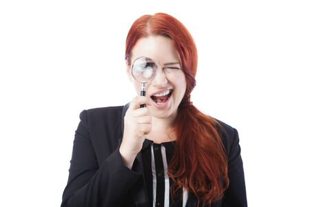 Pretty Young Businesswoman Spying Through Magnifying Glass Over the Eye with Open Mouth and Winking Eye. Isolated on White Background.の写真素材