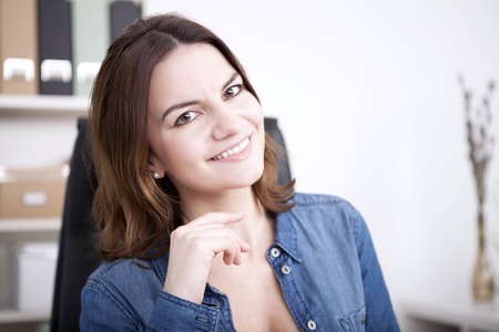 Close up Smiling Office Woman in Denim Shirt Looking at the Camera with Hands Close to her Face.の写真素材