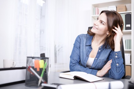 Close up Happy Thoughtful Office Woman Leaning on the Table with Pen and Book, Looking to the Upper Left of the Frame.の写真素材