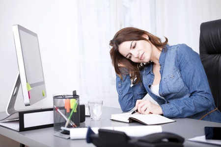 Close up Young Adult Businesswoman in Denim Shirt Reading a Book with Pen While Leaning at the Tableの写真素材