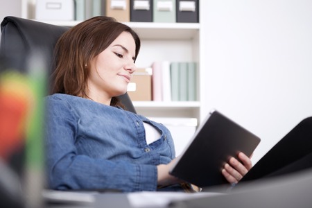 Close up Young Office Woman Relaxing at her Office Chair While Browsing at her Tablet Deviceの写真素材