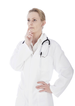 Portrait of a Pensive Woman Doctor Looking Far Left with Hands on her Chin and Waist. Isolated on White Background.の写真素材