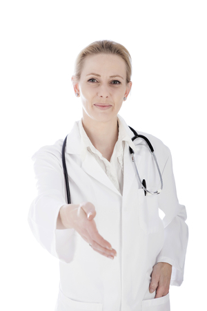 Close up Portrait of a Happy Woman Doctor Showing Hand Shake Gesture with One Hand in her Pocket and Looking at the Camera. Isolated on White Background.の写真素材