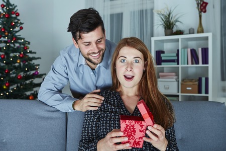 young couple is happy with gift for christmas in front of christmas treeの写真素材