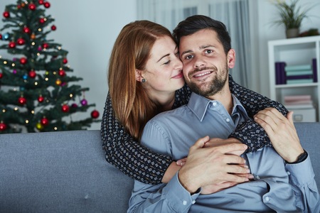 young happy couple hug on sofa and love christmas indoorsの写真素材