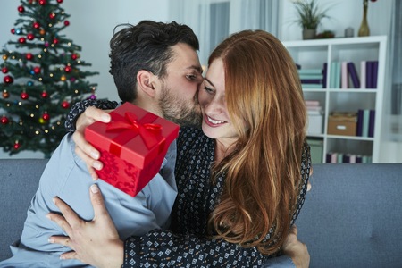 young couple is happy with gift for christmas in front of christmas tree