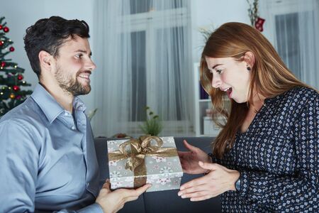 young man give her girlfriend a present box for christmas eve