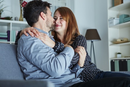 young happy couple hug on sofa and love christmas indoorsの写真素材