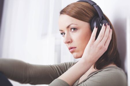 Good looking brown haired girl with headphones sitting and enjoys listening to music