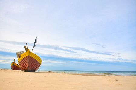 Fishing boat at baltic sea sandy beach with dramatic sky during summertime in Polandの写真素材