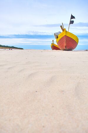 Fishing boat at baltic sea sandy beach with dramatic sky during summertime in Polandの写真素材