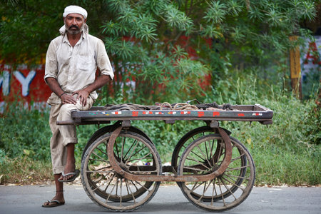 An Indian man with a cart on the street.