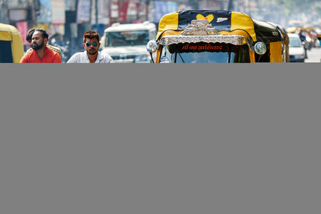 View of unknowns Nepali people driving a yellow tuk tuk taxi at Thamel street in Kathmandu in the...
