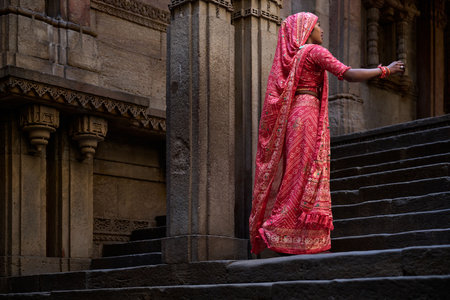 Indian woman in traditional red sari standing on the steps of a templeの写真素材