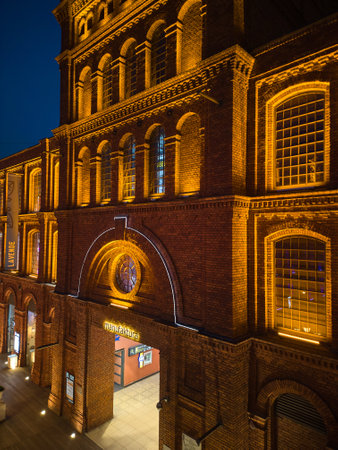 Nighttime View of Manufaktura in ÅÃ³dÅº, Poland, Illuminated by Warm Lighting Against the Historic Red Brick Buildings and Open Public Squareの写真素材