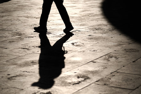 Shadow of a man walking on the street. Black and white photo.の写真素材