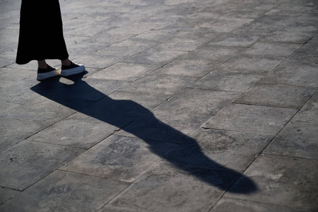 Shadow of a woman in a black dress walking on the street.の写真素材