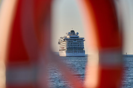 Artistic composition with blurred red lifebuoy framing cruise ship at sea in Gdansk.