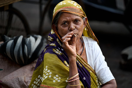 Unidentified Indian woman smoking a cigarette on the street.のeditorial素材