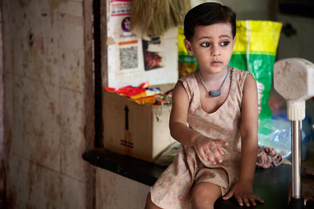 Portrait of a little girl sitting in front of her house.のeditorial素材