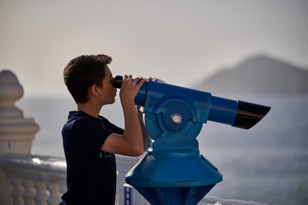 Tourist using blue coin operated telescope scenic viewpoint mountain landscape Benidorm Spain sightseeing activityのeditorial素材