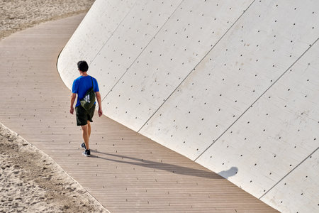 Person blue clothing walking curved white concrete amphitheater steps modern architecture Benidorm Spain urban tourismのeditorial素材