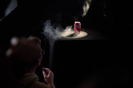 Coca-cola can in smoky spotlight on black table with audience member viewing, high-contrast studio...