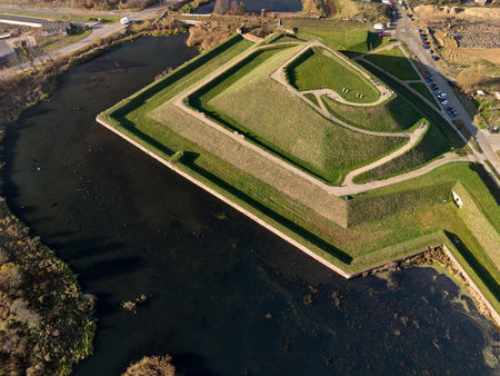 Aerial high-angle drone shot of 17th-century Gdansk star fort ramparts over water moat at sunset, moody landscape composition ideal for historical site promotion and travel brochureの写真素材