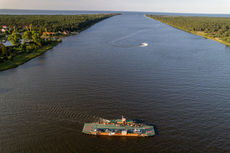 Ferry boat crossing water aerial perspective Gdansk Swibno-Mikoszewo route with forested shoreline...