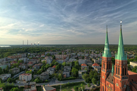 Aerial view of Rybnik skyline with Basilica towers in foreground and distant industrial chimneys on horizon, photographed in late afternoon light with clear sky and deep urban depth of field.の写真素材
