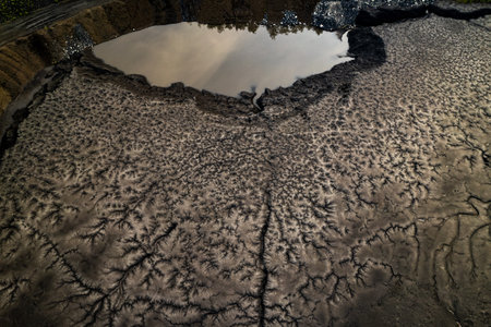Aerial water puddle cracked mud tire tracks mining area Rybnik Poland industrial landscape brown...