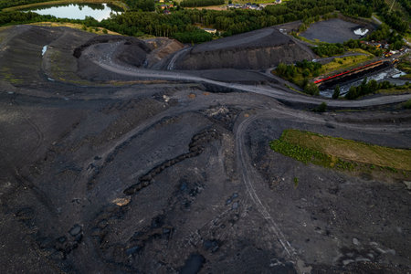 Red freight train transporting coal wagons railway track aerial view Rybnik Poland mining dump...