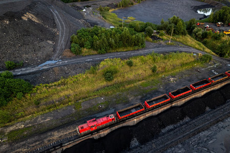 Red freight train transporting coal wagons railway track aerial view Rybnik Poland mining dump vegetation industrial horizontal landscape cargoの写真素材