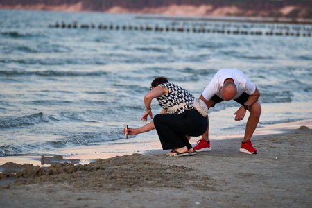 Couple exercising fitness training on sandy beach at sunset in Ustka