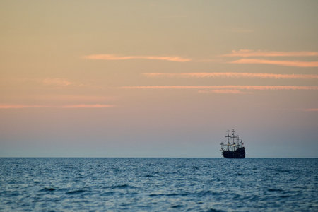 Tall ship silhouette on horizon at dusk, open ocean seascape, minimalist composition, tranquil...
