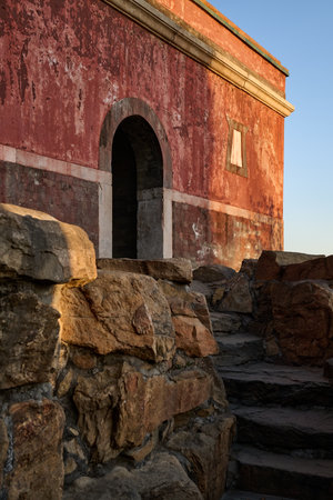 Ancient red fortress wall arched gateway entrance, weathered brick stone steps, golden hour light