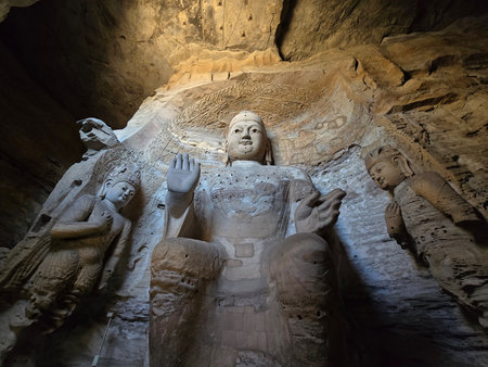 Interior Yungang Grotto with multiple Buddha statues and decorated ceiling featuring lotus motifs and celestial figures, cave architecture, natural illuminationの写真素材