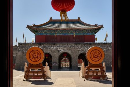 Red lantern framed through dual dragon medallions ancient temple gateway traditional Chineseの写真素材