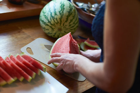 Woman Slicing Fresh Watermelon on Kitchen Counterのeditorial素材