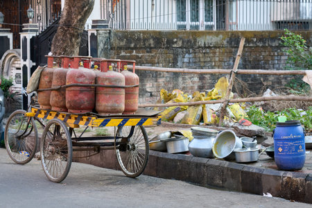 Tricycle cart carrying gas cylinders near street pots
