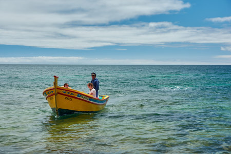 People riding in a traditional yellow fishing boat named Oasis on the open ocean, Albufeira, Algarve, Portugalのeditorial素材